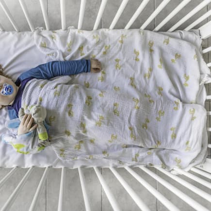 Rothaariges Kleinkind mit Schnuller liegt schlafend im Gitterbett Rothaariges Kleinkind mit Schnuller liegt schlafend im Gitterbett