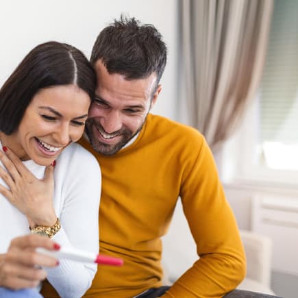Paar schaut lachend auf einen Schwangerschaftstest. Paar schaut lachend auf einen Schwangerschaftstest.