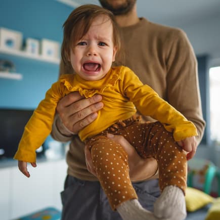 Kind schreit auf Papas Arm. Kind schreit auf Papas Arm.