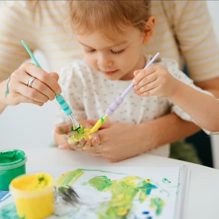 Mädchen bastelt zusammen mit ihrer Mutter ein Bild mit Handabdruck Mädchen bastelt zusammen mit ihrer Mutter ein Bild mit Handabdruck
