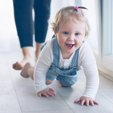 Kleines Mädchen krabbelt grinsend über den Fußboden. Kleines Mädchen krabbelt grinsend über den Fußboden.