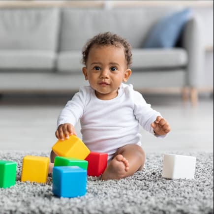 Ein kleiner Junge sitzt auf dem Boden und spielt mit Bauklötzen. Ein kleiner Junge sitzt auf dem Boden und spielt mit Bauklötzen.