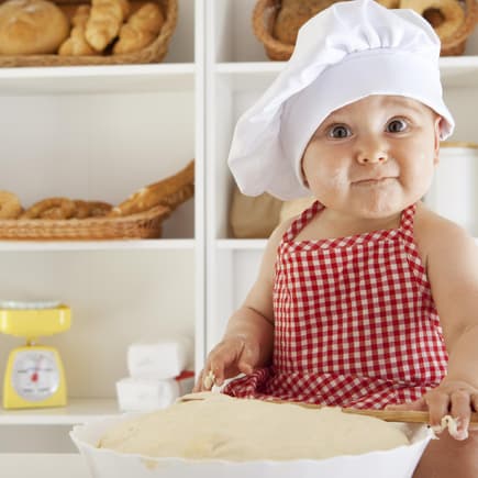Brot ist auch schon für Babys geeignet. Baby mit Bäckermütze macht Brotteig.