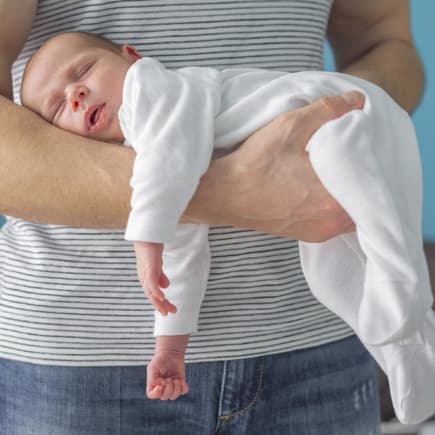 Der Fliegergriff als Allheilmittel für Babys wird zunehmend abgelehnt. Ein Vater hält sein Neugeborenes im Fliegergriff vor seinem Bauch