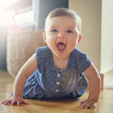 Baby-Mädchen robbt auf dem Boden und lacht mit offenen Mund. Baby-Mädchen robbt auf dem Boden und lacht mit offenen Mund.
