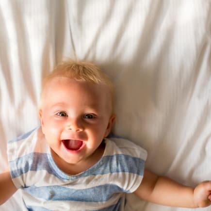 Baby-Junge liegt auf dem Bett und lacht. Baby-Junge liegt auf dem Bett und lacht.