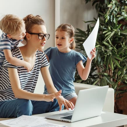 Arbeiten mit Kindern kann für Eltern Stress bedeuten Frau am Laptop mit zwei Kindern.