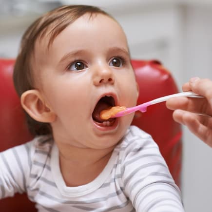 Ein kleines Kind isst einen Löffel Brei aus einem Babygläschen. Ein kleines Kind isst einen Löffel Brei aus einem Babygläschen.