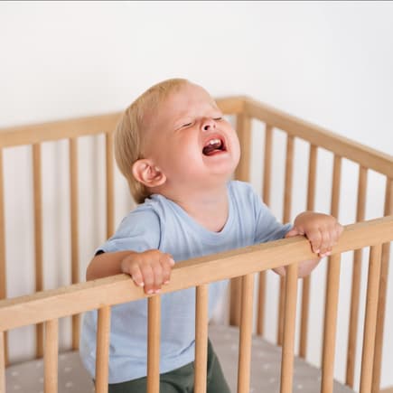 Wenn das Schlafengehen zu Trotzanfällen führt ... Ein Kleinkind wird im Kinderbett wütend