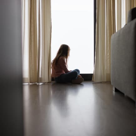 Wie Eltern die mentale Gesundheit ihrer Kinder schützen können Ein Kind sitzt allein am Fenster