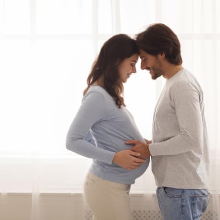 Bevor das Kind kommt, sollten sich Eltern zwei wichtige Fragen stellen. Schwangere Frau und Mann umarmen sich.