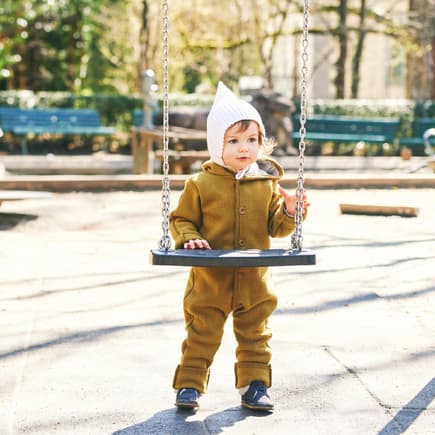Ein Kleinkind im beliebten Wollwalkoverall Ein Kleinkind im Wollwalkoverall auf dem Spielplatz
