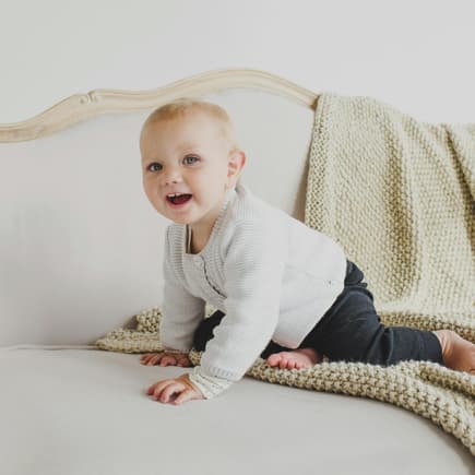 Altdeutsche Mädchennamen sind total im Trend. Kleines Mädchen sitzt auf Sofa.