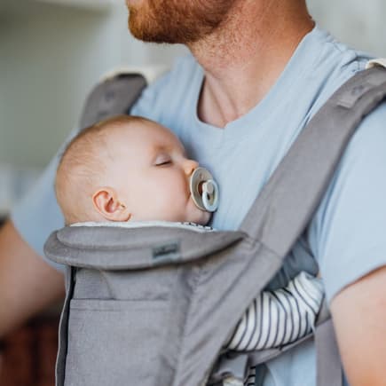 Wenn Baby am liebsten in der Trage schläft Ein Baby schläft bei Papa in der Trage mit Schnuller