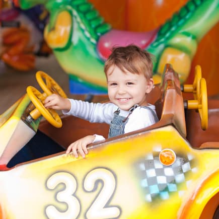 Ein Freizeitpark macht auch den Kleinsten schon gute Laune. Ein kleiner Junge im Auto im Freizeitpark.