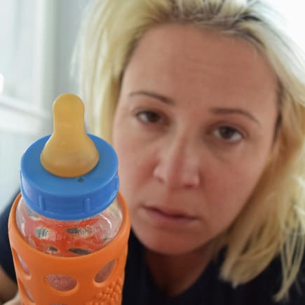 Schlafmangel bei Müttern Eine Mutter, die eine Flasche in der Hand hält ...