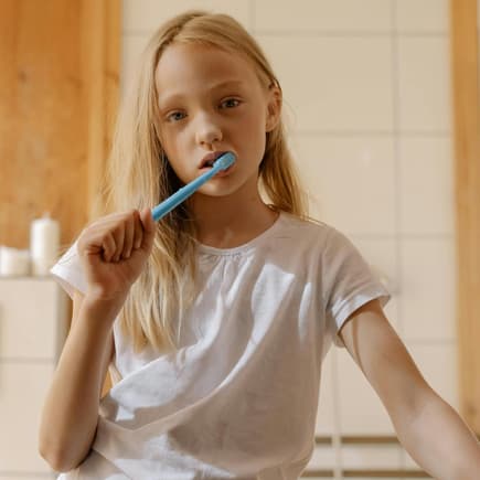 Ohne Zähneputzen ins Bett? Ein Mädchen, das gelangweilt die Zähne putzt.