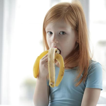 Eine Banane hilft beim Einschlafen. Kind isst Banane.