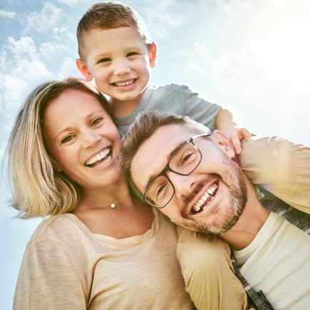 Oft wünschen sich Männer ein weiteres Kind und Frauen nicht. Eltern mit Kind lachen in die Kamera.