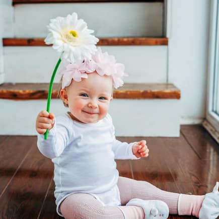 Blumennamen für Blumenmädchen. Ein kleines Baby, das eine Blume hält.