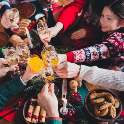Anstoßen innerhalb der Familie – auch Kinder sind gern dabei. Zu Weihnachten stößt eine Familie mit Gläsern an.