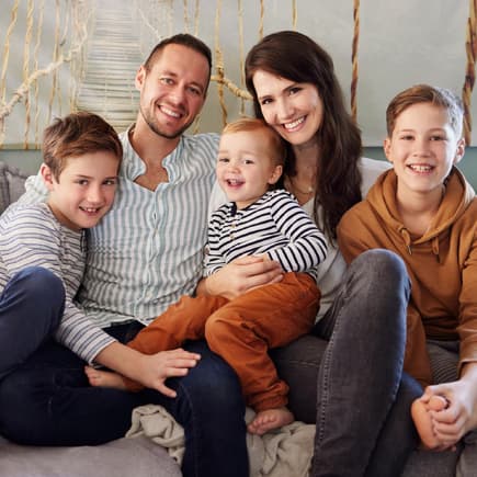Für Familien gibt es 2025 einige Gesetzesänderungen. Familie mit drei Kindern sitzt auf dem Sofa.