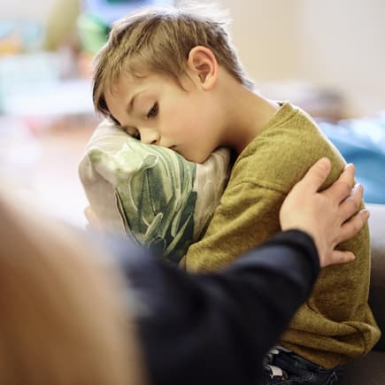 Manchmal wäre man als Mama am liebsten überall gleichzeitig. Mutter tröstet krankes Kind.