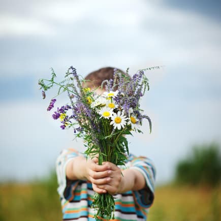 Frühling mit Kindern ist einfach die schönste Jahreszeit. Junge hält Blumenstrauß in die Kamera.