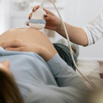 Der Wehenschmerz wird individuell unterschiedlich wahrgenommen. Schwangere Frau beim Ultraschall.