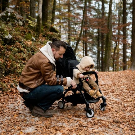Viele Kinder wollen ihre Eltern vom Buggy aus sehen. Vater mit Kind im Herbstwald.