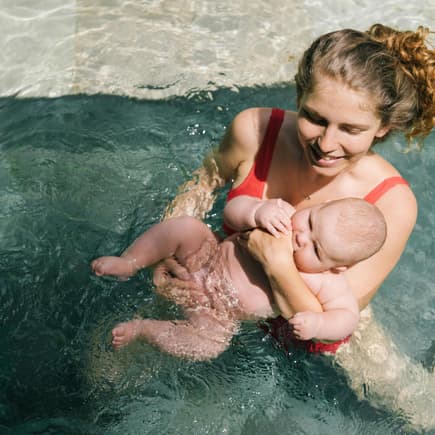 Das Babyschwimmen ist anfangs eher eine Wassergewöhnung. Mutter mit Baby im Wasser.