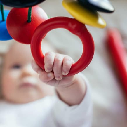 Greif mich mal! Ein Mobile lässt Babys erste Sinne erwachen. Baby greift nach einem Mobile.