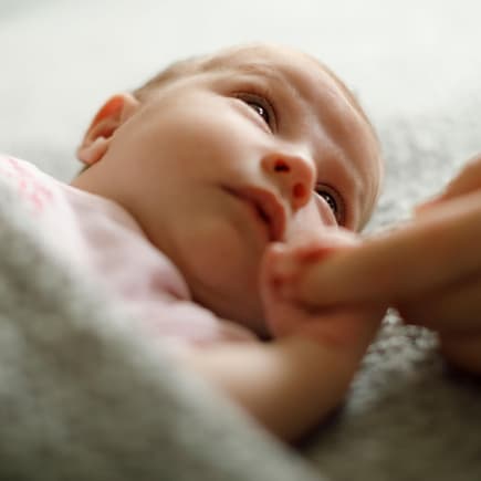 Wenn ihr wollt, dass euer Baby einschläft, solltet ihr auf diesen häufigen Fehler beim Ins-Bett-Bringen achten. Müdes Baby hält Finger eines Elternteils.