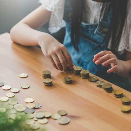 Im Familienleben Geld zu sparen ist gar nicht so schwer – mit den richtigen Tricks. Mädchen zählt Münzen.