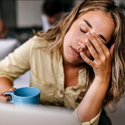 Das Gefühl, weder dem Job noch dem Kind gerecht zu werden, kennen bestimmt viele arbeitende Mütter ... Erschöpfte Frau mit Kaffeebecher.