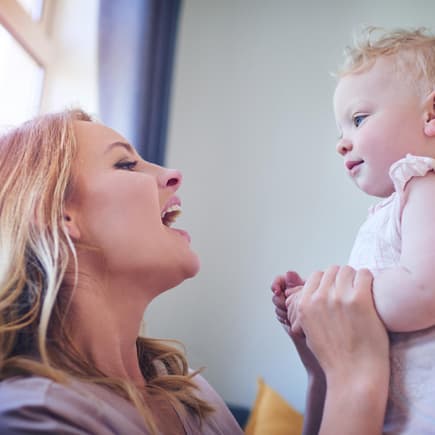 Eltern können ihre Kinder bei der Sprachentwicklung unterstützen. Mutter spricht mit ihrem Baby.