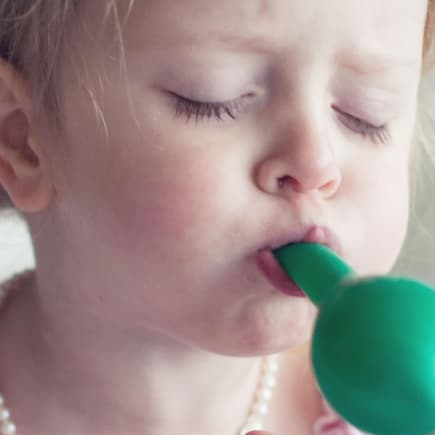 Luftballons können für kleine Kinder tatsächlich gefährlich sein. Mädchen pustet einen Luftballon auf.
