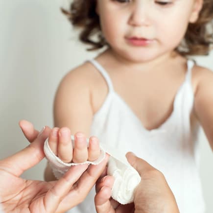 Autsch! Eingeklemmte Finger kommen bei Kindern leider schnell mal vor. Kind bekommt einen Verband um die Hand.