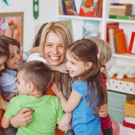 Ein Abschied fällt immer schwer – auch von der Lieblingserzieherin. Kinder umarmen Erzieherin.