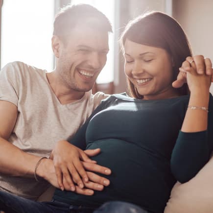 Durch Reden, Streicheln, Musik oder Gedanken kann zum Baby im Bauch Kontakt aufgenommen werden. Paar streichelt den Babybauch.