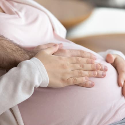 Mama und Papa können mit dem Baby schon Kontakt aufnehmen, wenn es noch im Bauch ist. Das ist gut für die pränatale Bindung. Frau und Mann legen Hände auf Babybauch.