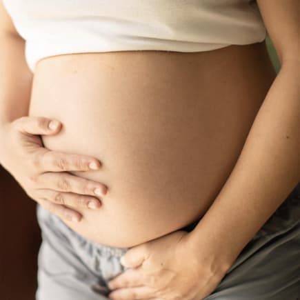 Inkontinenz in der Schwangerschaft – damit haben viele Frauen zu tun. Schwangere hält sich den Bauch und die Blase.