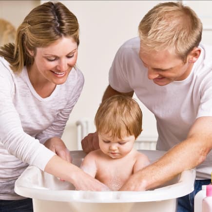 Mit Kindern ist immer viel zu tun, da ist eine Arbeitsteilung notwendig. Eltern baden ihr Kleinkind.