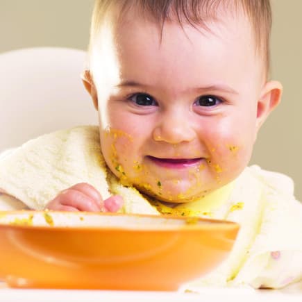 Der erste Brei ist für Babys etwas ganz Aufregendes. Und für Mamas und Papas meist auch. Baby mit breiverschmiertem Mund.