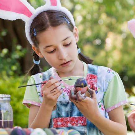 Ostereier bemalen gehört zu den Feiertagen einfach dazu. Zwei Kinder bemalen Ostereier im Garten.
