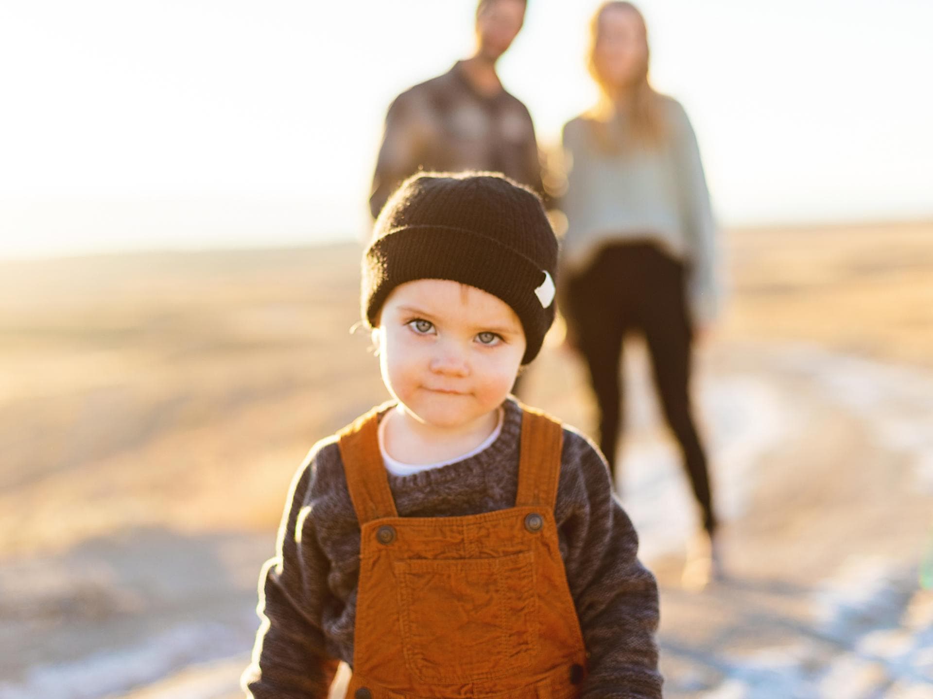 Plattdeutsche Namen Ein kleiner Junge mit Wollmütze und Latzhose, der mit seinen Eltern am Strand ist.