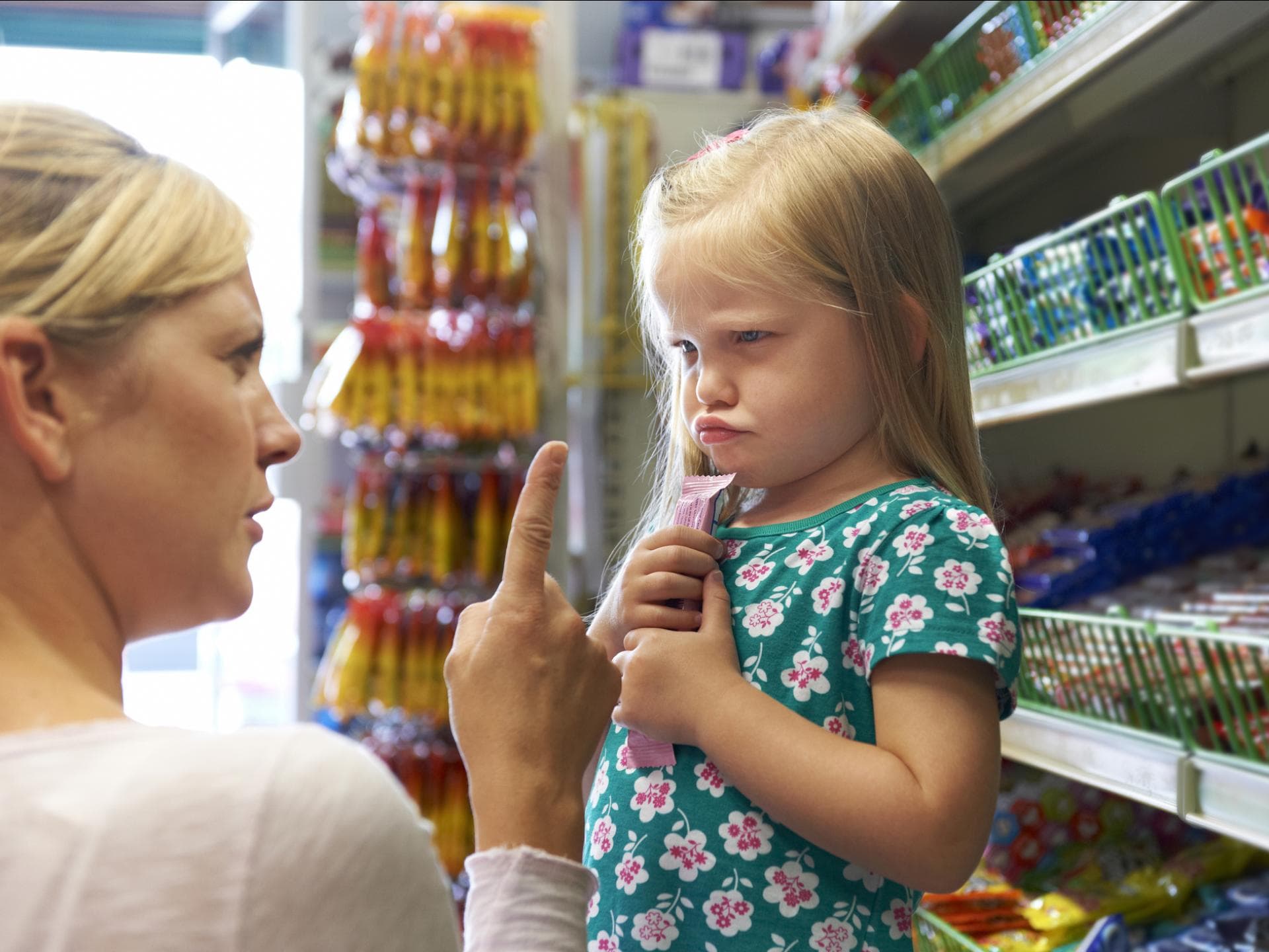 Mama schimpft mit ihrer Tochter, die im Supermarkt einen Riegel geholt hat Mama schimpft mit ihrer Tochter, die im Supermarkt einen Riegel geholt hat