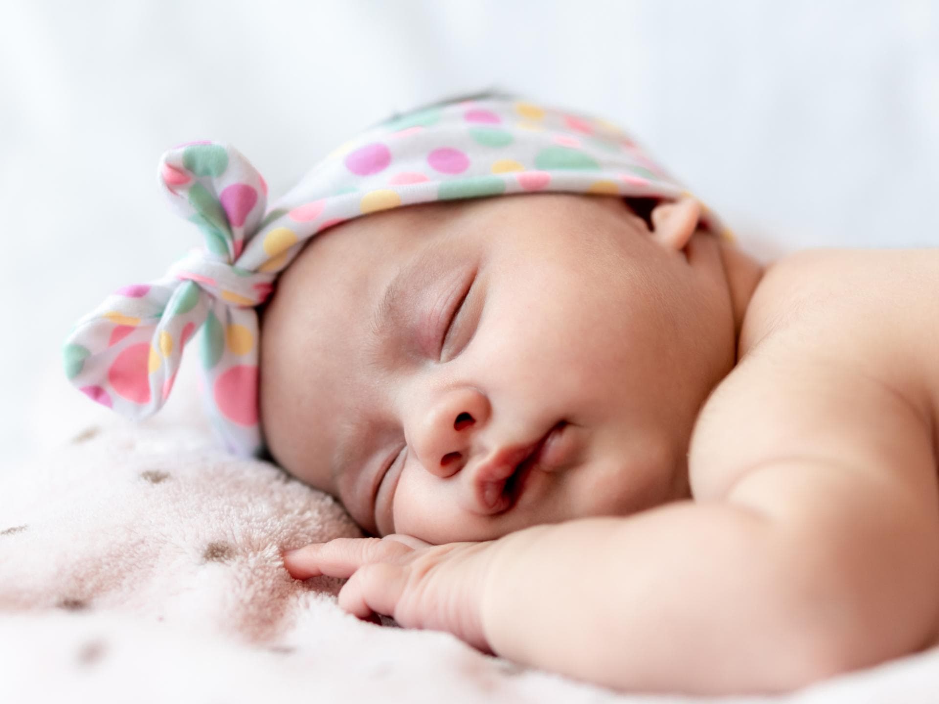 Hier findet ihr eine Auswahl an Mädchennamen mit P. Ein Baby liegt schlafend auf dem Bauch.