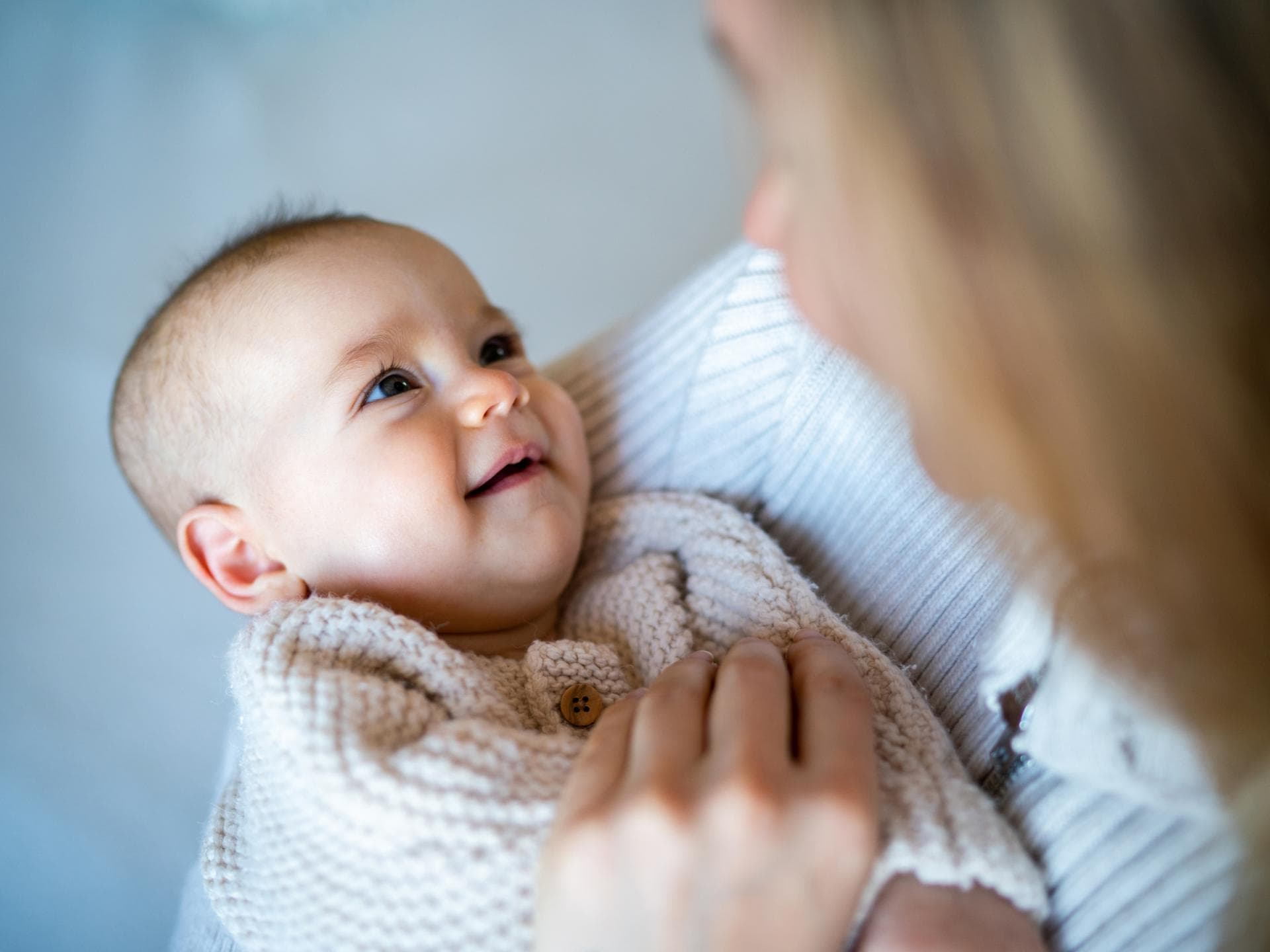 Dieser Artikel liefert Inspiration für Jungennamen mit Q! Ein kleiner Junge liegt in Mamas Armen.