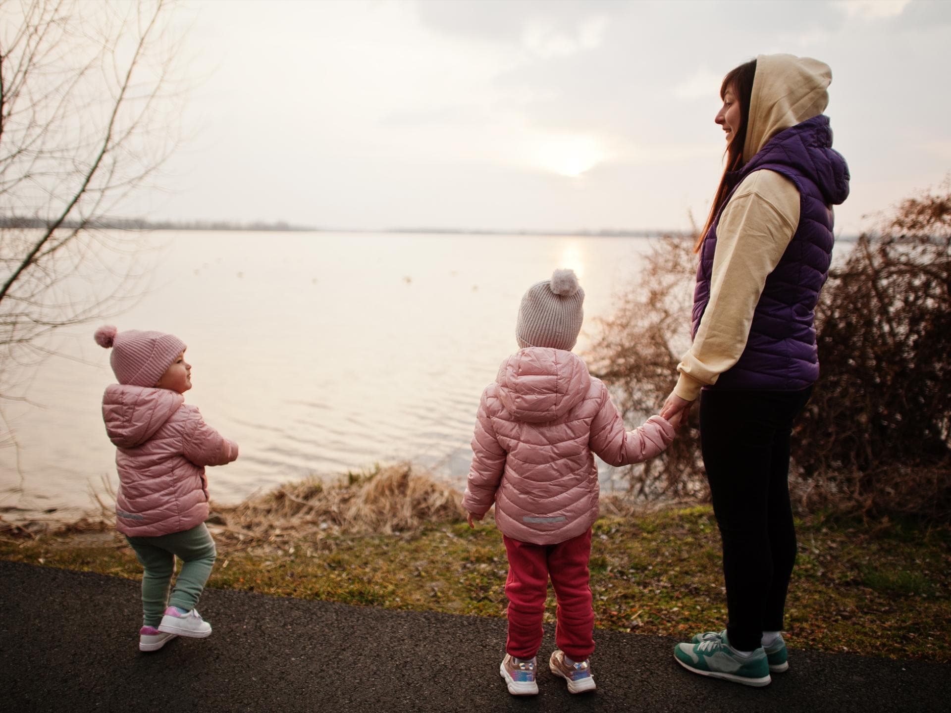Wenn eine Mutter mit ihren Kinder nicht zu U-Untersuchungen geht, wirft das Fragen auf. Mutter steht mit zwei kleinen Mädchen am See.